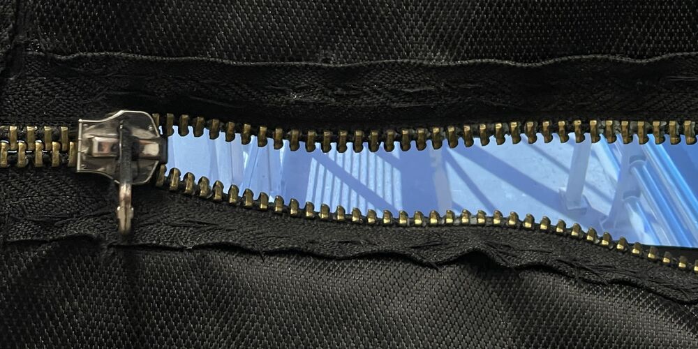 A blue live feed glowing through the open zipper of a black backpack
