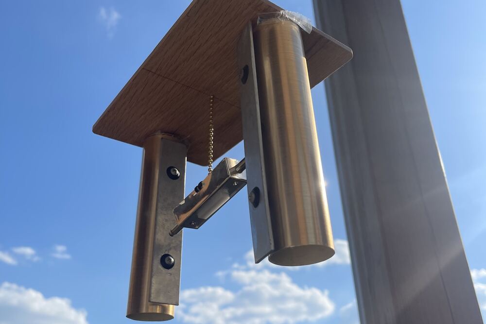 The chime from below, its brass tubes catching the sun