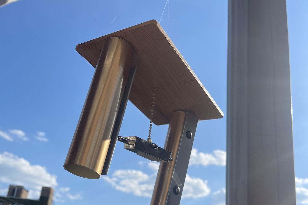 The chime turning in the air, buildings and clouds behind it