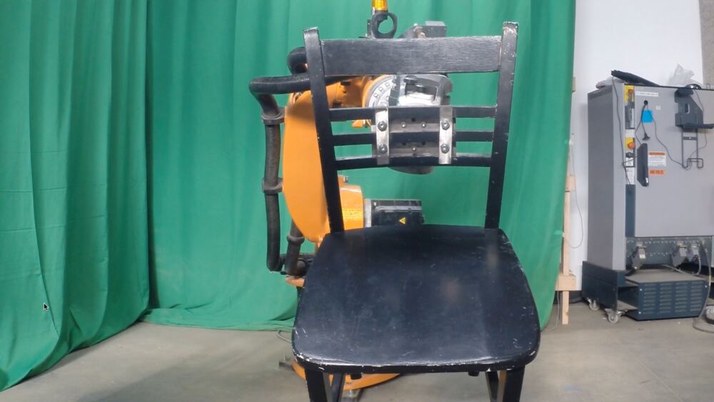 From the front, the chair held up by the arm behind it, its seat facing the camera