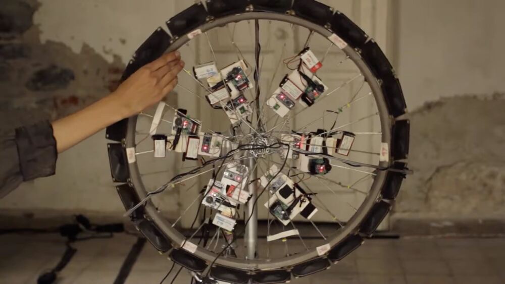 A hand turning the wheel, speakers and FM receivers fixed to its spokes