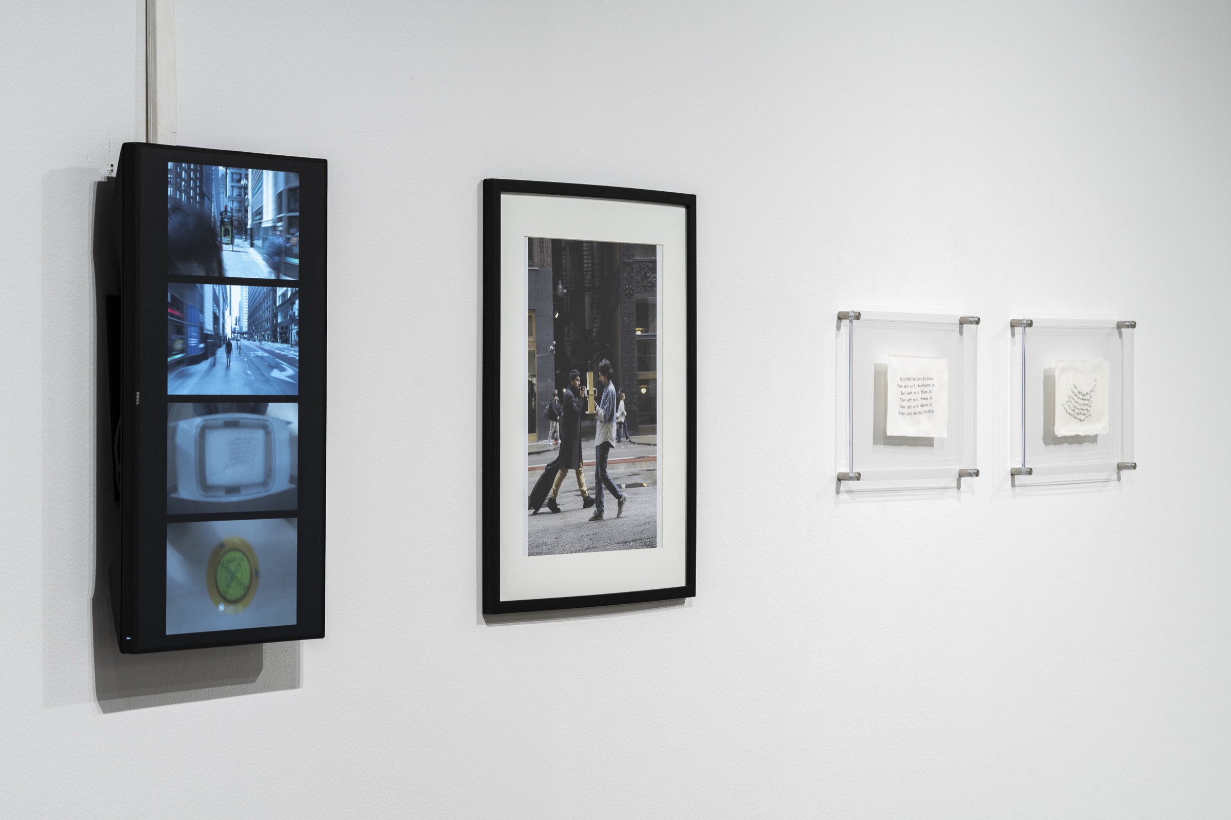 A vertical screen, a framed photograph and two mounted sheets of paper