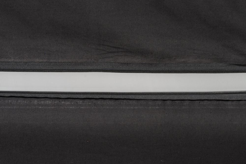 Light through the opening of a zipper across a black curtain