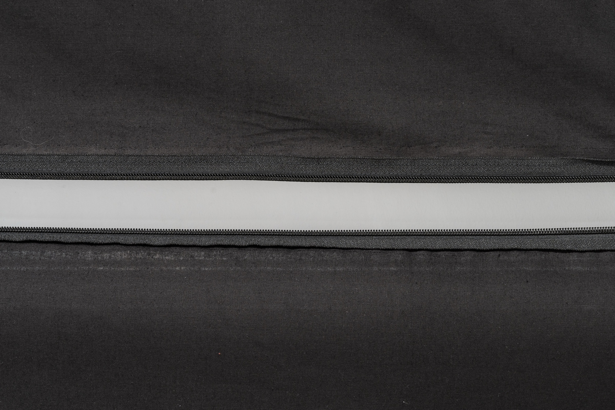 Light through the opening of a zipper across a black curtain