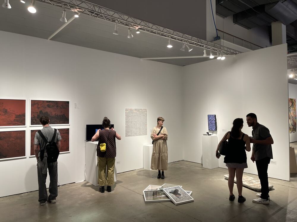 The piece across the gallery, visitors looking at the works around it