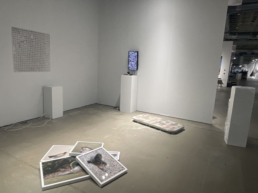 The piece at the far end of the space, past prints laid on the floor