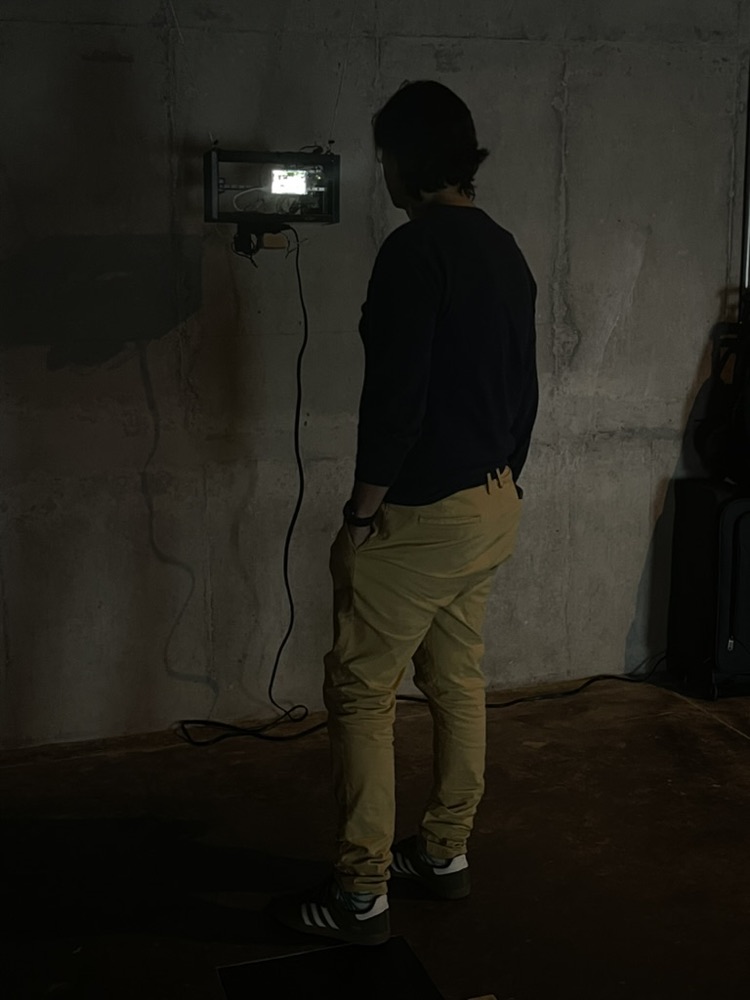A visitor standing in the dark in front of the glowing screen